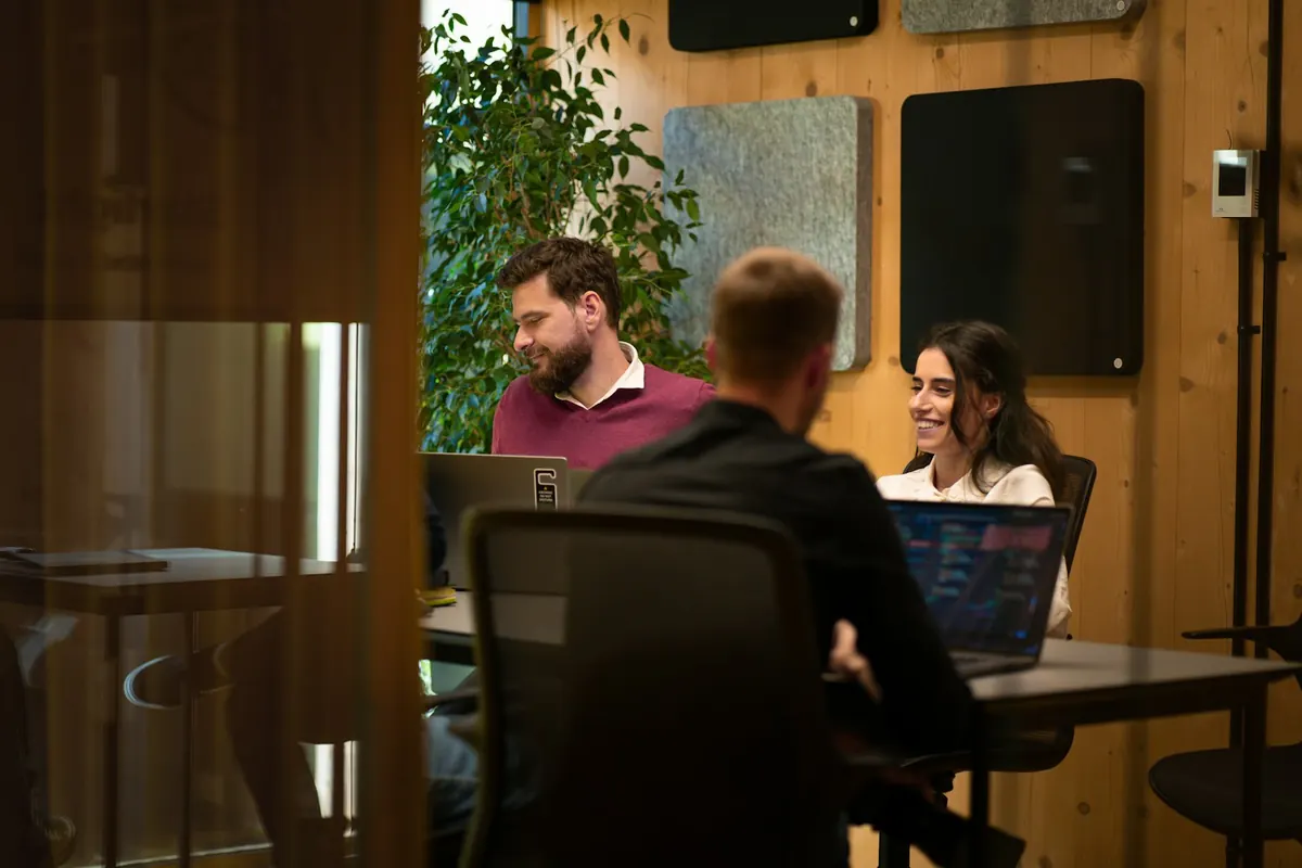 Colleagues working across desks in a warm-lit office