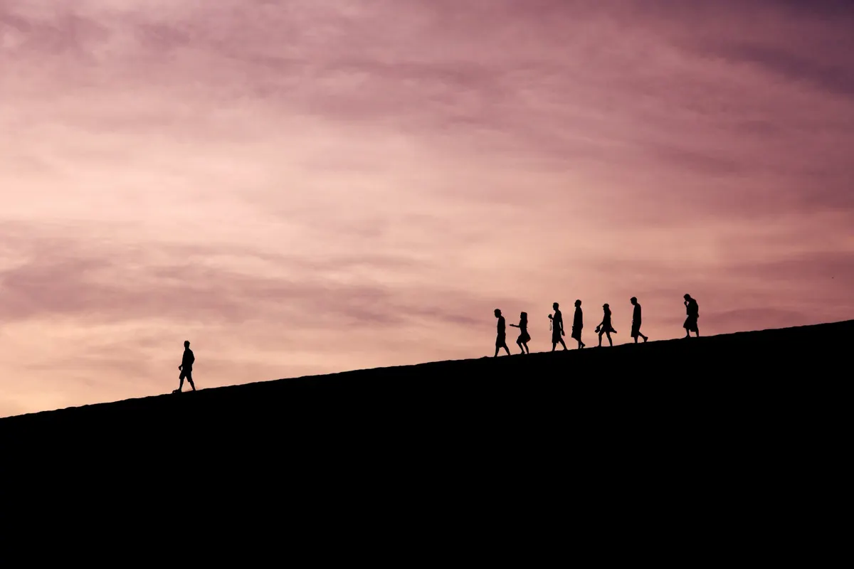Walkers silhouetted along a ridge at dusk