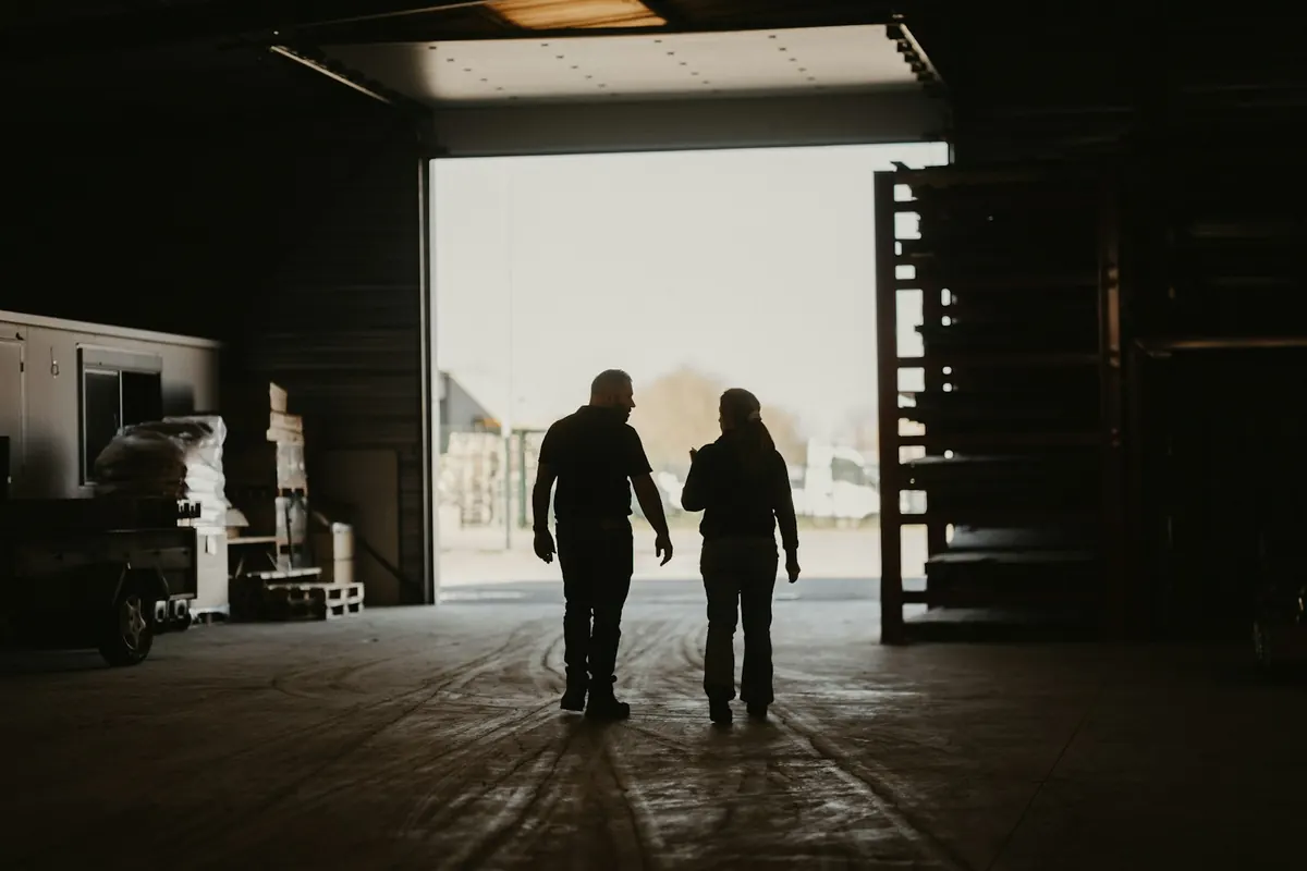 Two workers silhouetted in the doorway of a warehouse