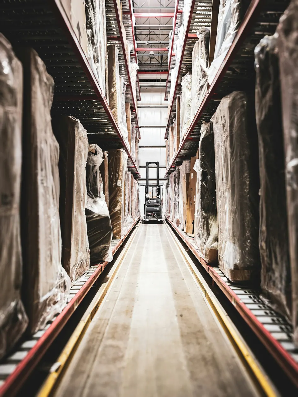 A narrow corridor between tall storage racks, lit from above