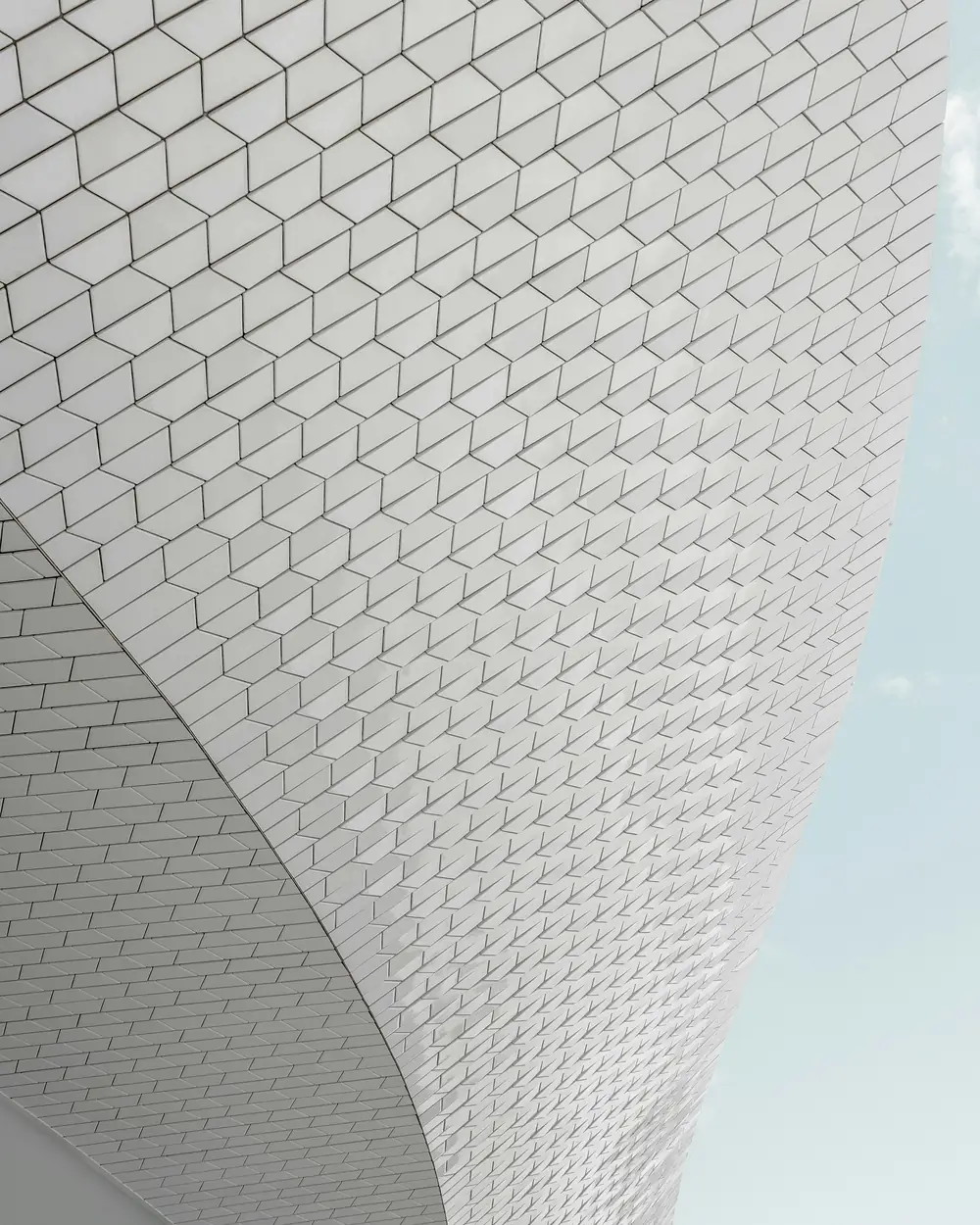 A pale tiled facade curving away against an open sky