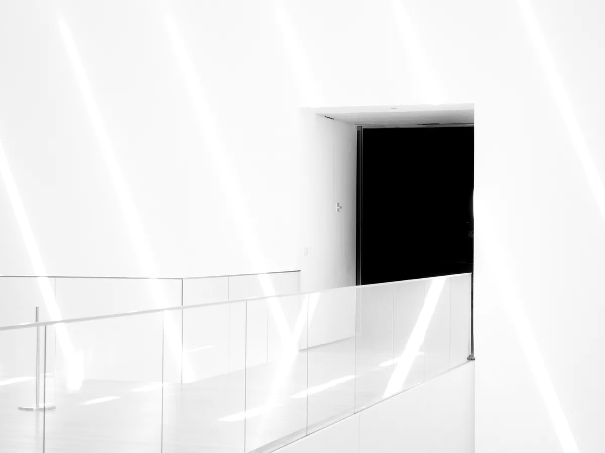 An open doorway in a bright white interior, daylight falling across the floor