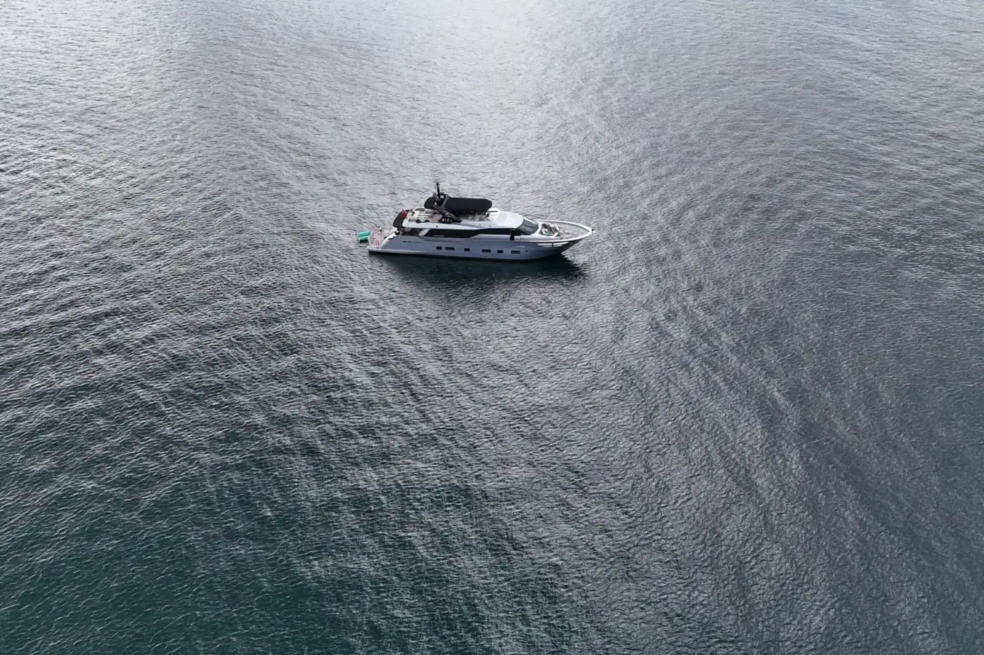 A single vessel on open silver water, seen from above