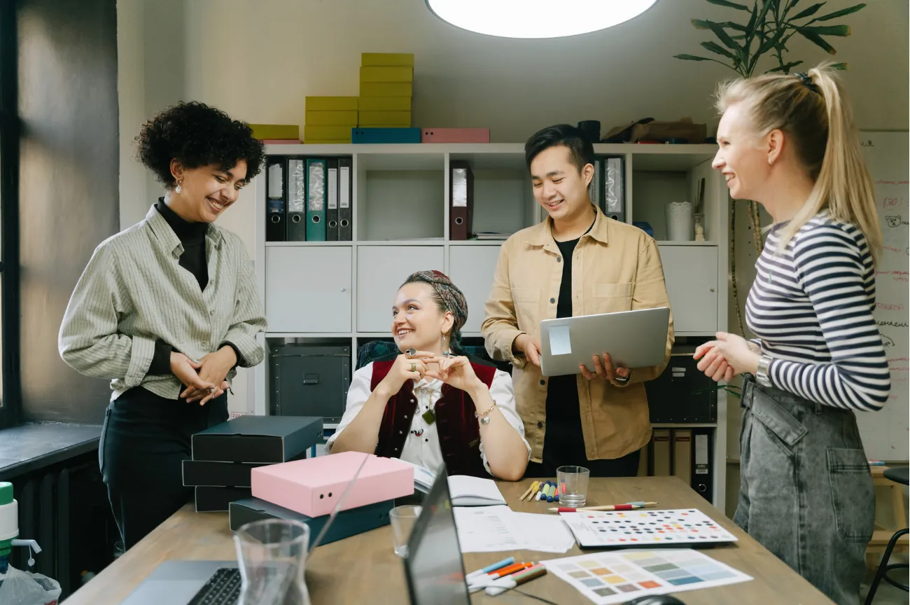 Four colleagues talking through printed worksheets around an office table