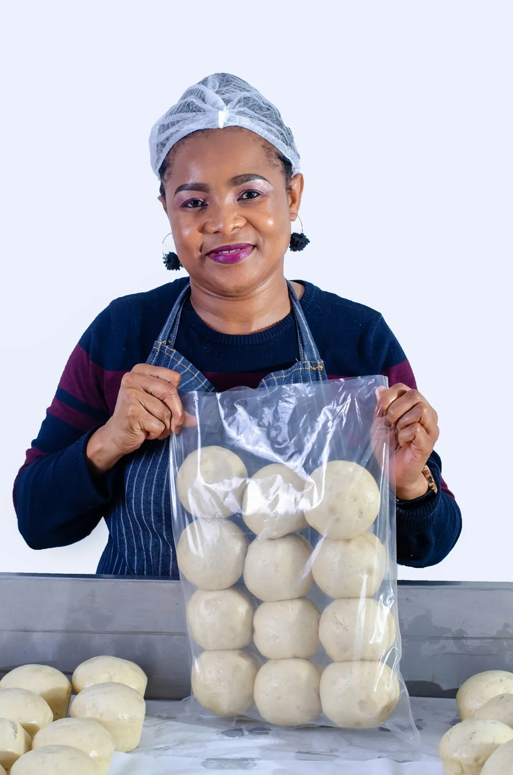 A baker holding a bag of fresh dough rounds